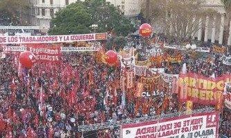 La escena refleja un acto político del Frente de Izquierda Una multitud de personas se encuentra en Plaza de Mayo. Predominan los colores rojo, amarillo y blanco, con numerosas banderas, pancartas y grandes globos rojos flotando sobre el grupo. Se leen letreros con consignas políticas, incluyendo menciones al 'Frente de Izquierda de los Trabajadores', 'Partido Obrero' y 'Izquierda Socialista'. La escena refleja un acto político del Frente de Izquierda Una multitud de personas se encuentra en Plaza de Mayo. Predominan los colores rojo, amarillo y blanco, con numerosas banderas, pancartas y grandes globos rojos flotando sobre el grupo. Se leen letreros con consignas políticas, incluyendo menciones al 'Frente de Izquierda de los Trabajadores', 'Partido Obrero' y 'Izquierda Socialista'.